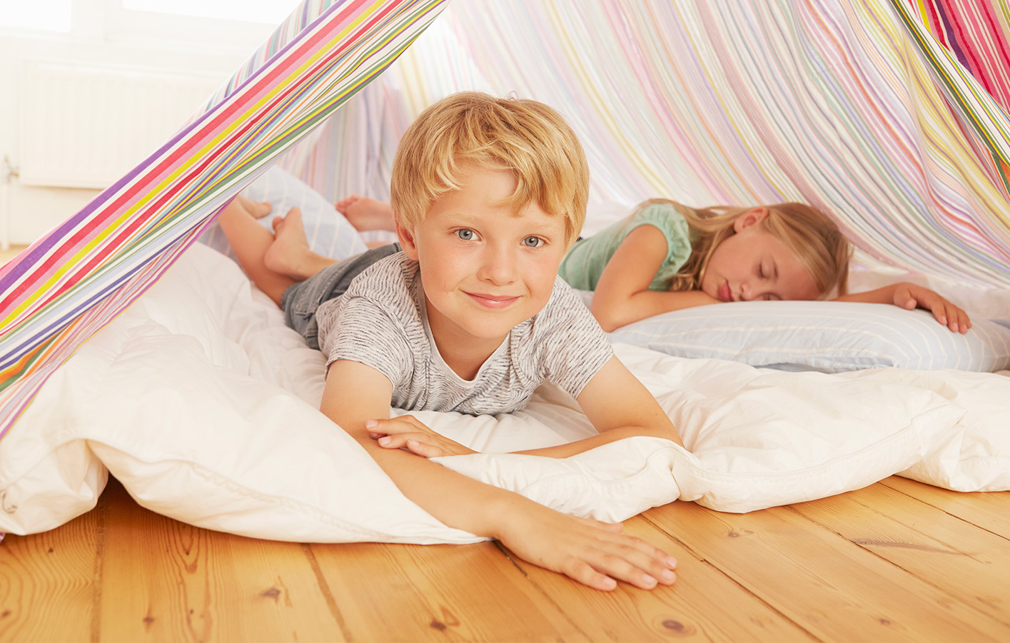 Kinder entspannen auf einem Holzboden und spielen in einer gemütlichen Wohnumgebung